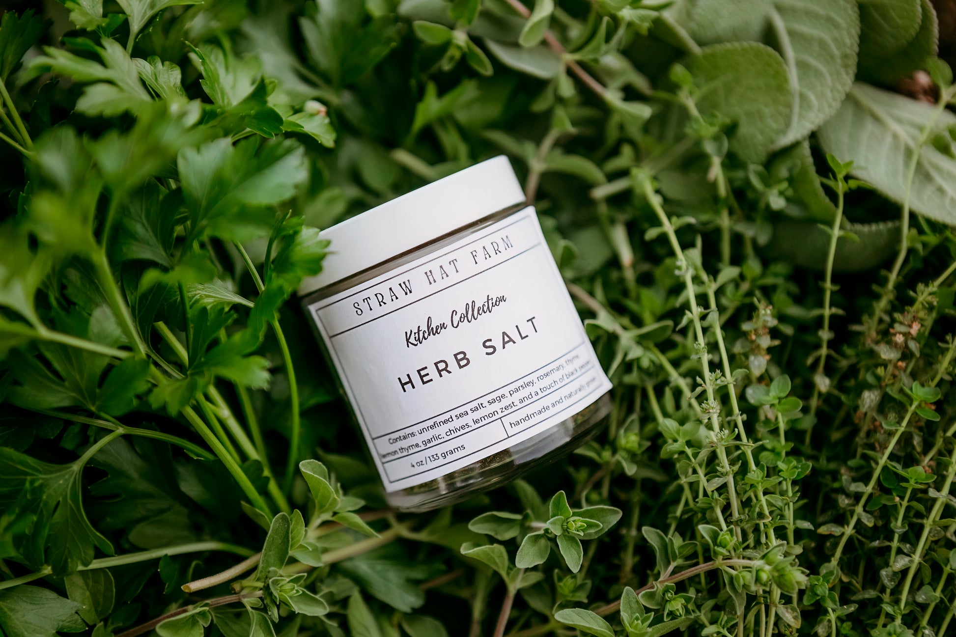 a jar of herb salt resting on a bed of fresh herbs